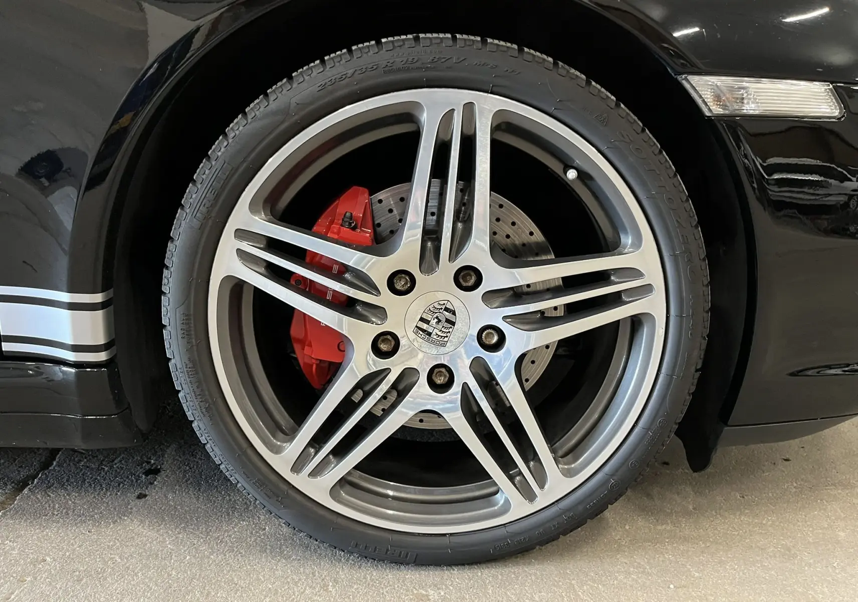 Gros plan sur la jante Turbo 19 pouces bi-ton avec étrier de frein rouge d'une Porsche 911 Targa 997 Carrera 4S noir métallisé.