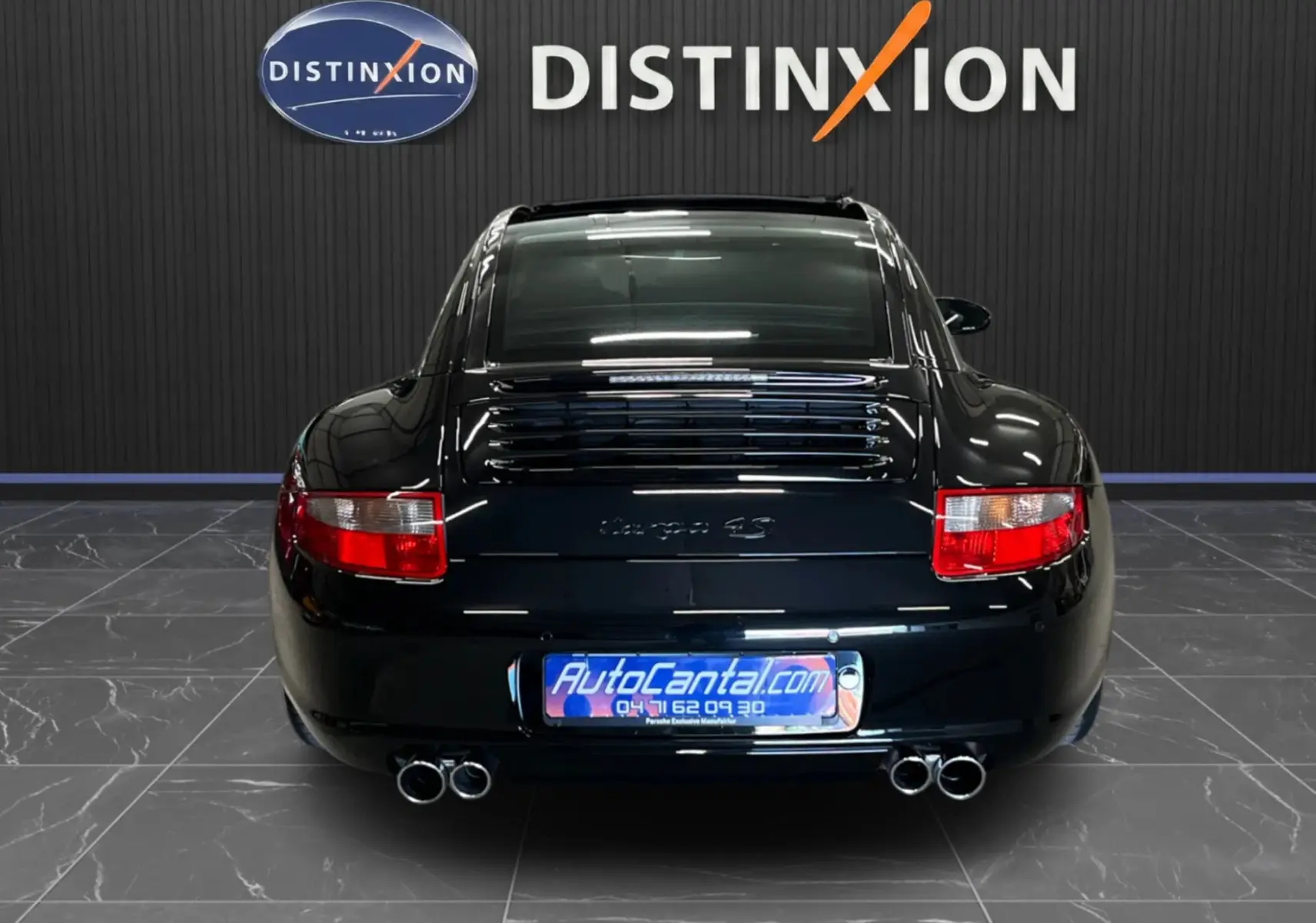 Vue arrière d'une Porsche 911 Targa 997 Carrera 4S noire métallisée avec doubles sorties d'échappement et feux rouges.