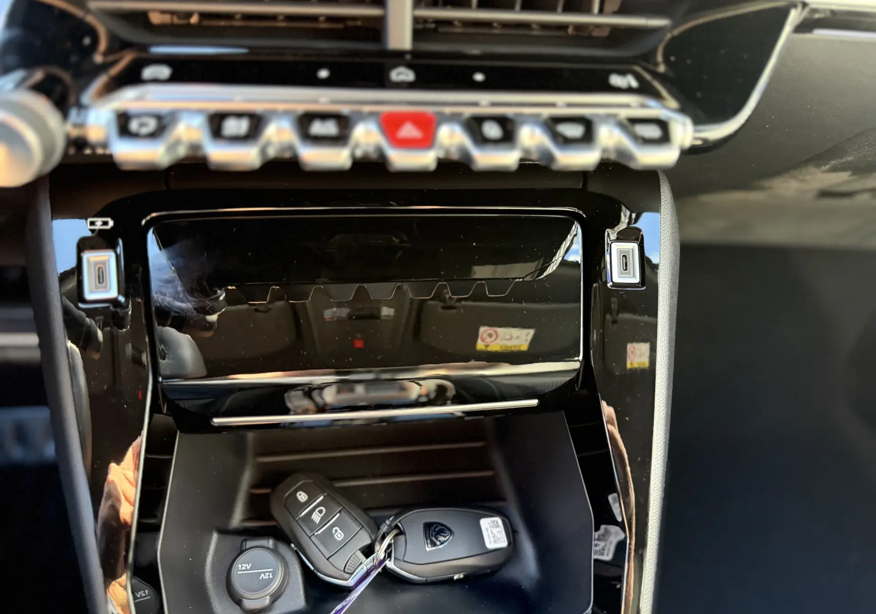 Gros plan intérieur sur la console centrale noire brillante du Peugeot 2008 Hybrid 145 GT avec clé posée dans le rangement.