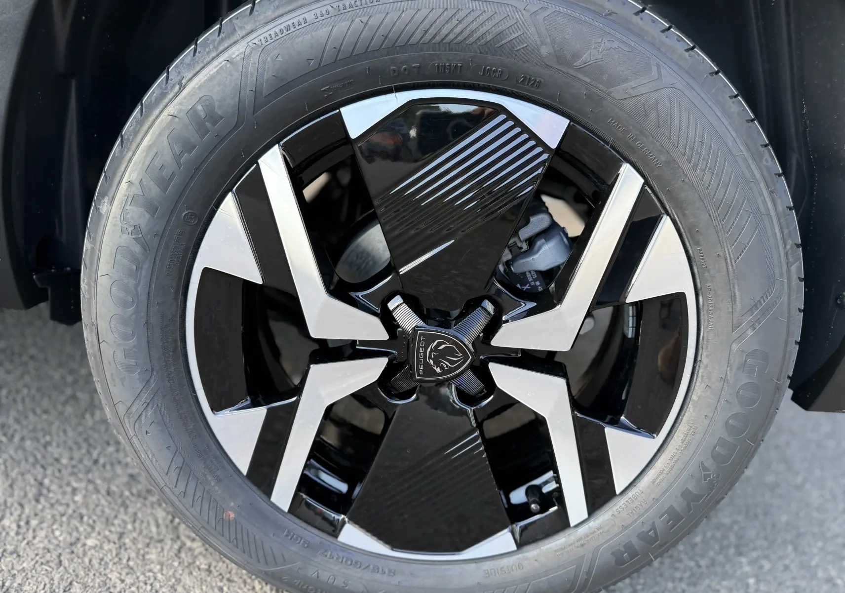 Gros plan sur la jante noire et argentée du Peugeot 2008 Hybrid 145 gris Artense, mettant en valeur le logo lion central.