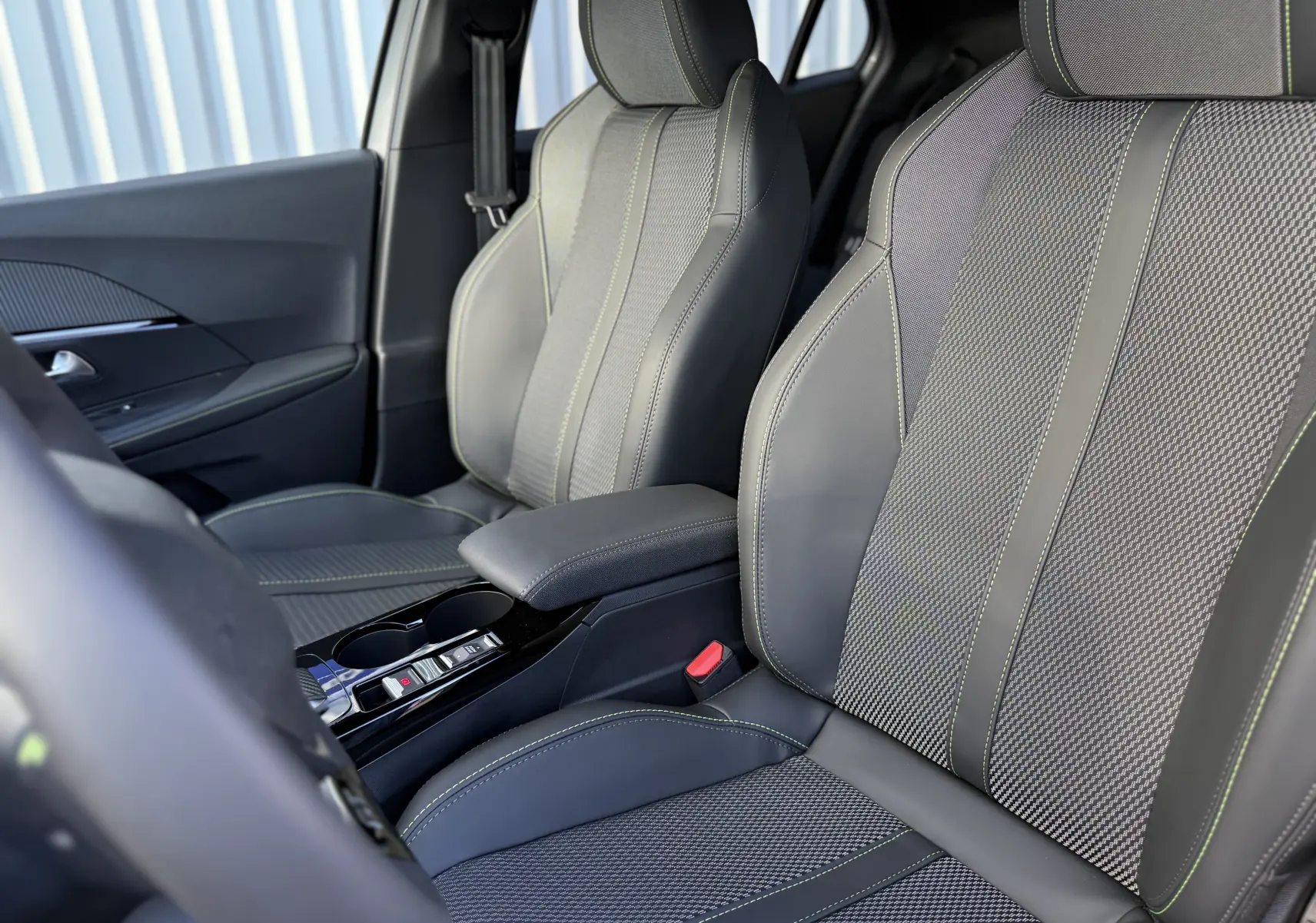 Gros plan sur les sièges avant en cuir et tissu gris avec surpiqûres vertes du Peugeot 2008 Hybrid 145 CH GT.