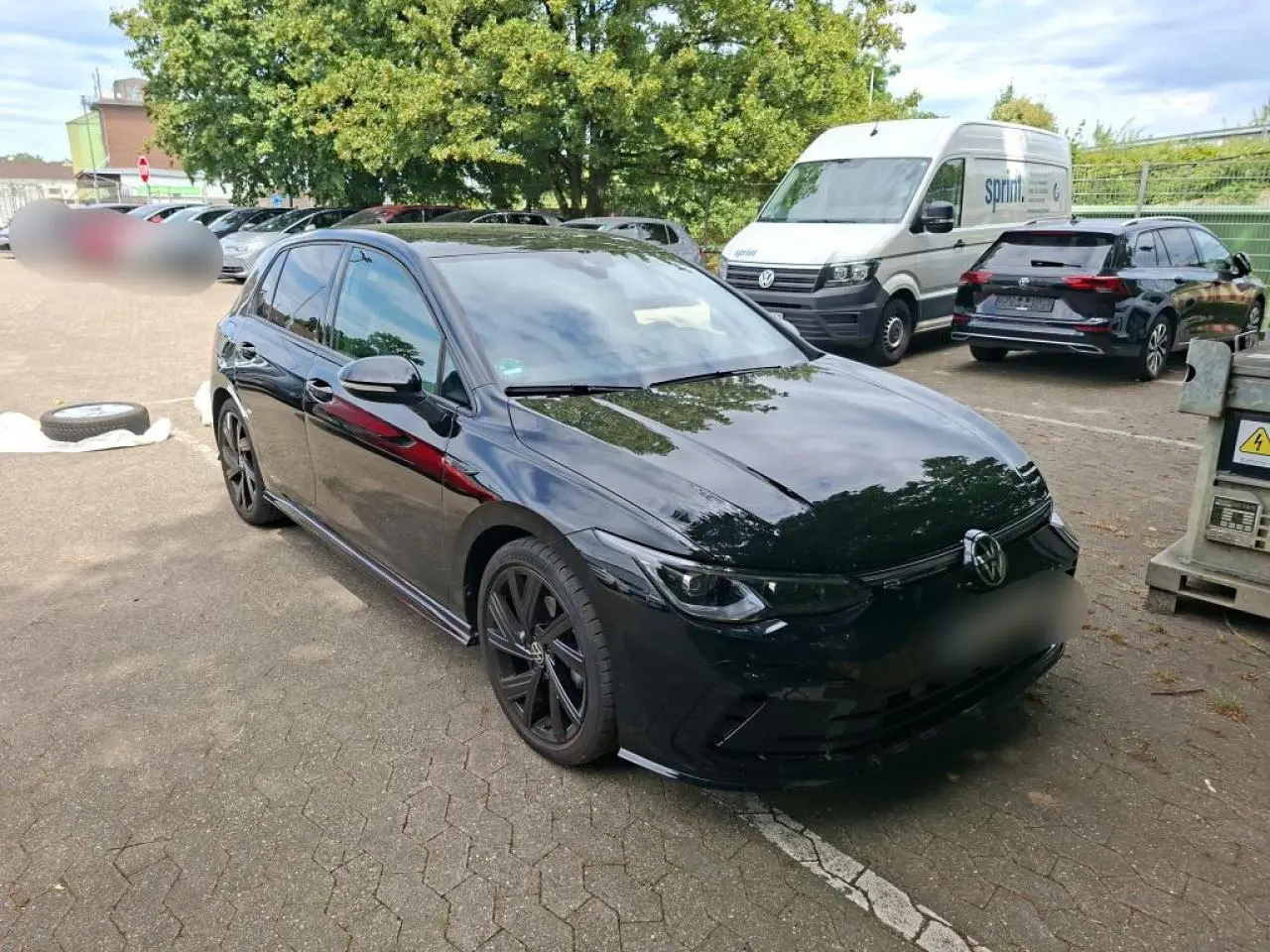 Volkswagen Golf 8 R-Line noire vue 3/4 avant avec jantes noires et attelage escamotable visible.