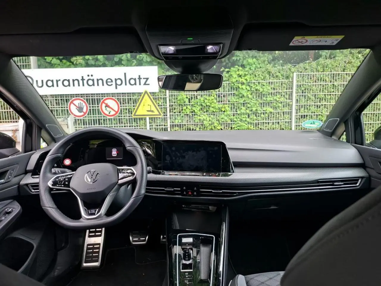 Vue intérieure avant de la Volkswagen Golf 8 noire, mettant en valeur le volant multifonction et l'écran tactile central.