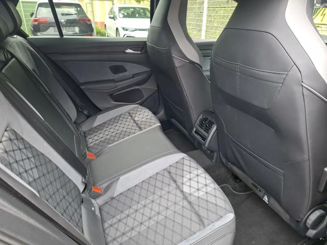 Vue intérieure arrière côté droit de la Volkswagen Golf 8 R-Line 2024 avec sellerie tissu et ArtVelours gris à motifs.