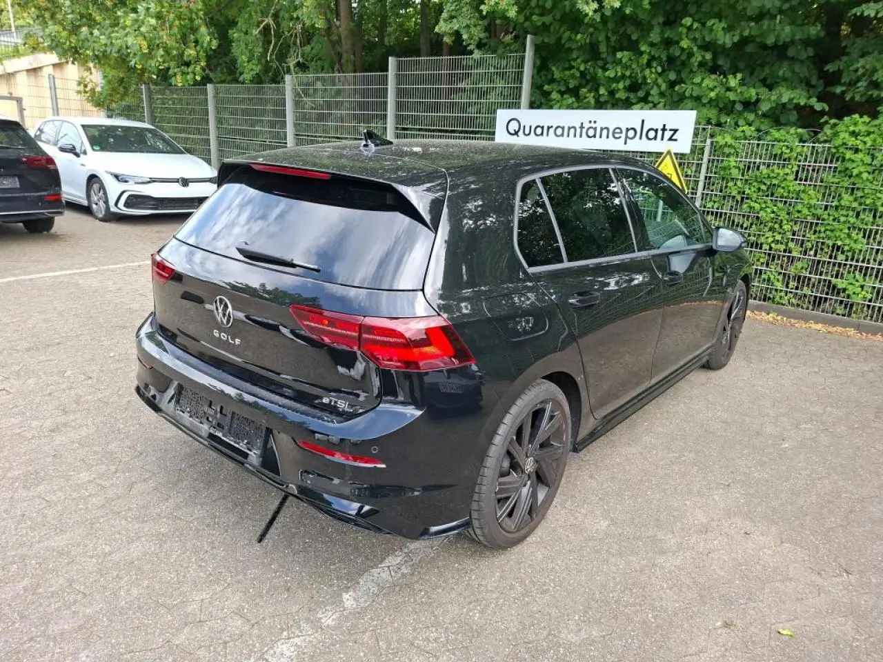 Vue 3/4 arrière droite d'une Volkswagen Golf 8 noire avec jantes alliage noires et vitres teintées.