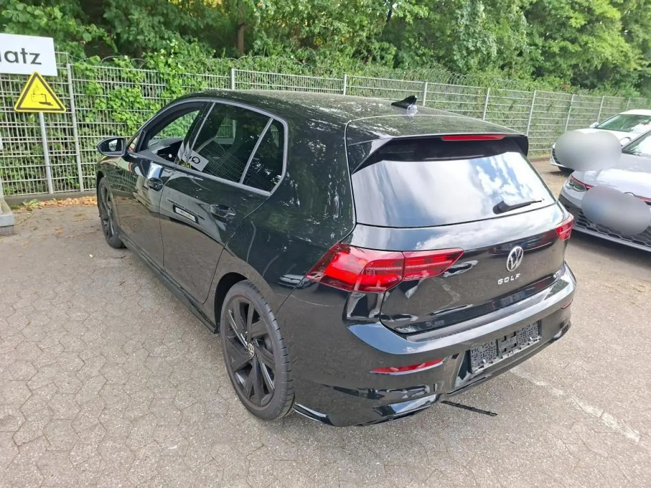 Volkswagen Golf 8 R-Line noire vue 3/4 arrière droit, avec jantes noires et feux arrière LED défilants.