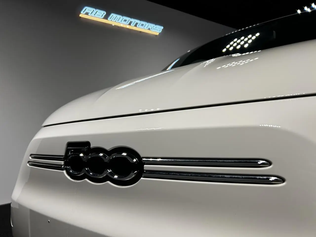 Gros plan sur la calandre avant blanche de la FIAT 500 électrique 2024 avec logo 500 noir brillant.