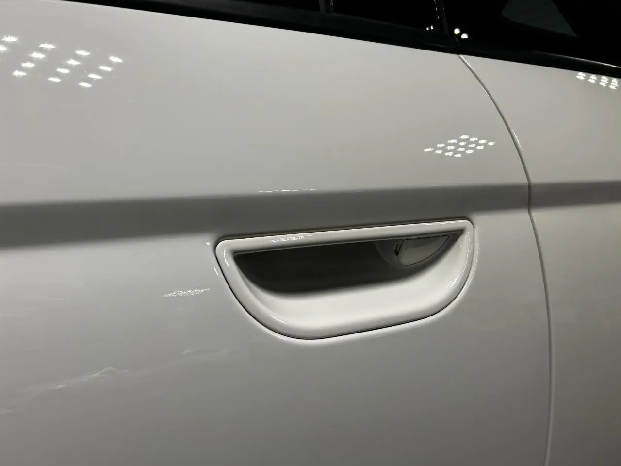Poignée de porte blanche en gros plan sur le côté gauche d'une FIAT 500 électrique 2024.