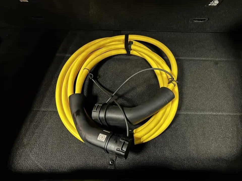 Câble de recharge jaune enroulé dans le coffre d'une FIAT 500 électrique blanche 2024.