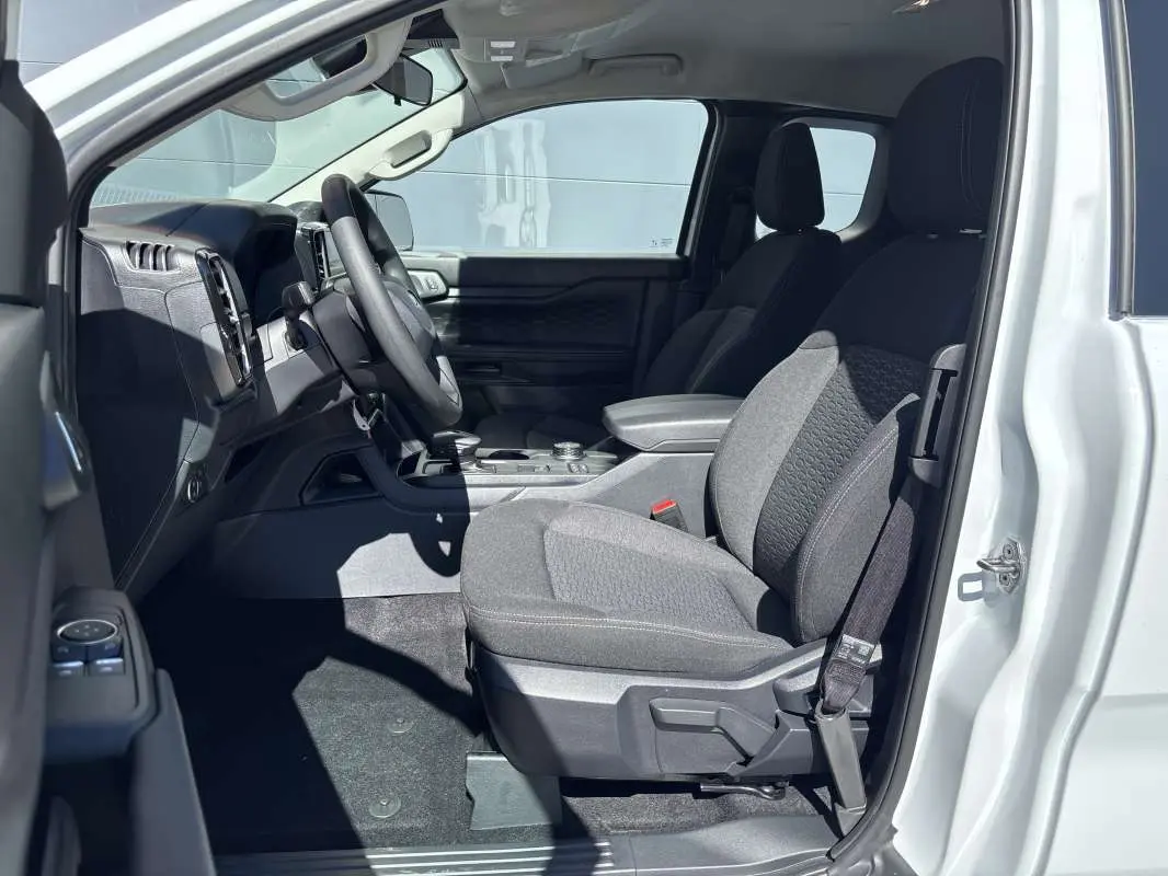 Vue intérieure côté conducteur du Ford Ranger blanc glacier 2026, sièges tissu gris et tableau de bord moderne.