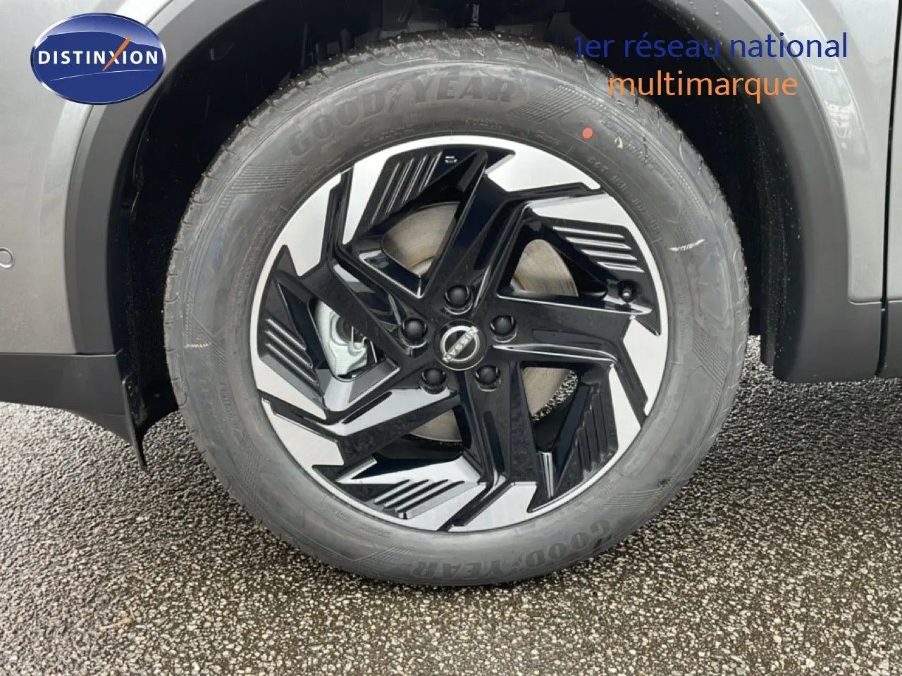 Gros plan sur la roue avant gauche du Nissan Qashqai gris squale métal avec jante noire et argentée au design moderne.