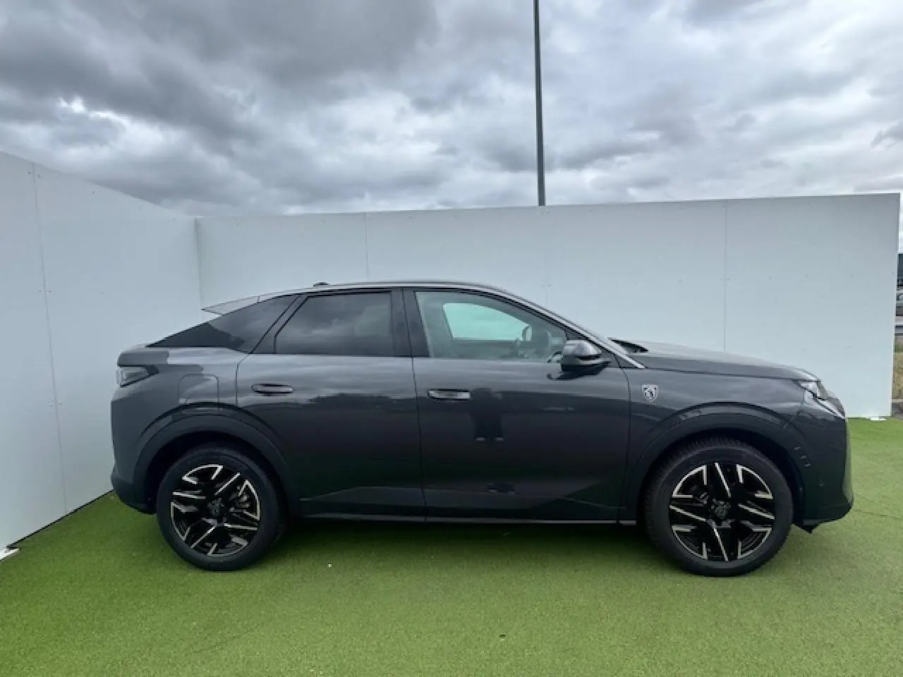 Vue de profil côté gauche d’un Peugeot 3008 gris titane avec toit noir et jantes alliage noires diamantées.