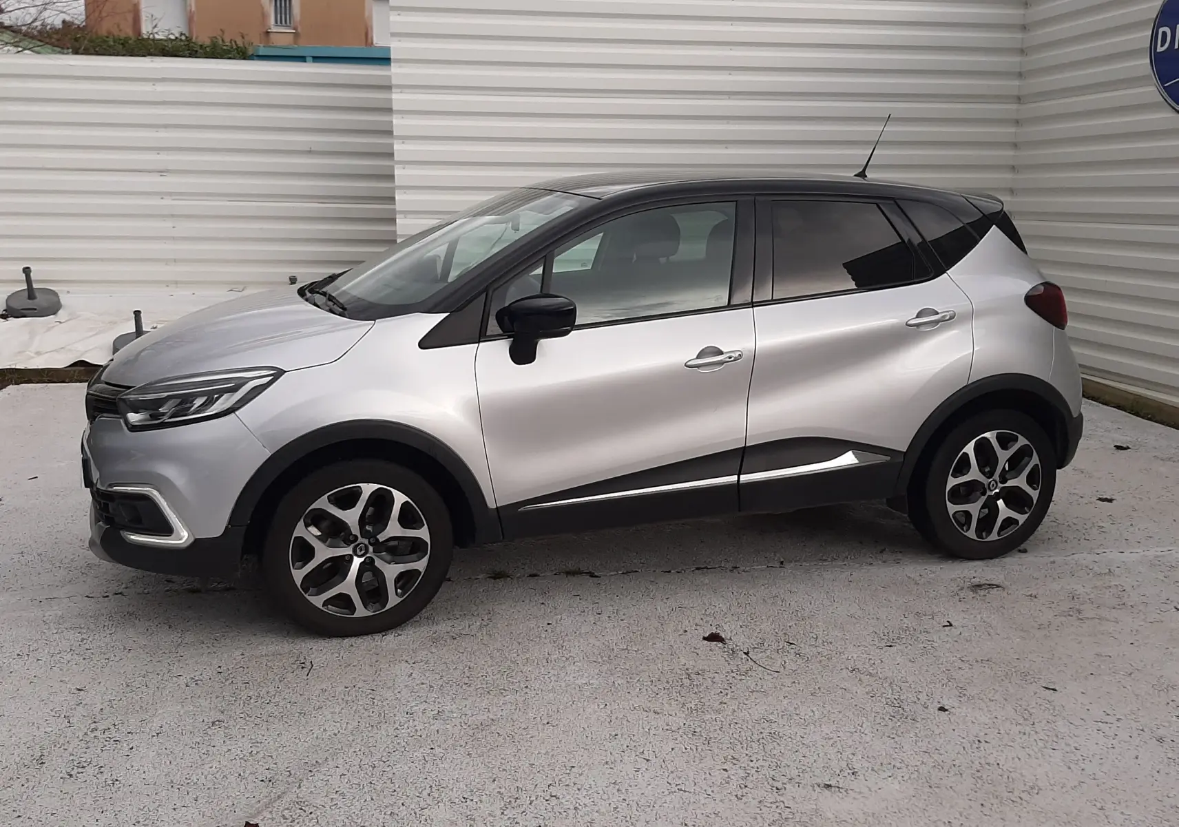 Vue de profil droit du Renault Captur gris avec toit noir, soulignant ses jantes alliage et ses lignes modernes.
