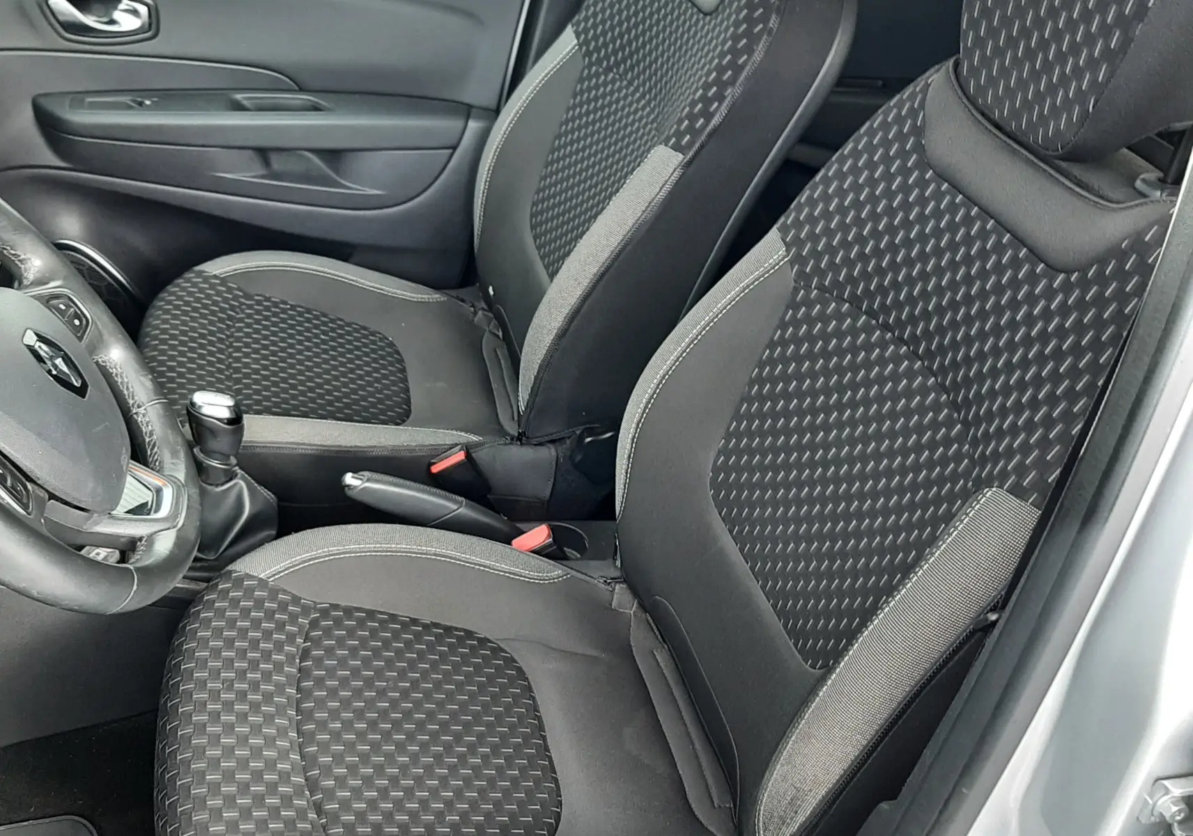 Vue intérieure côté conducteur du Renault Captur 2017, sièges noirs avec motifs géométriques et volant multifonction.