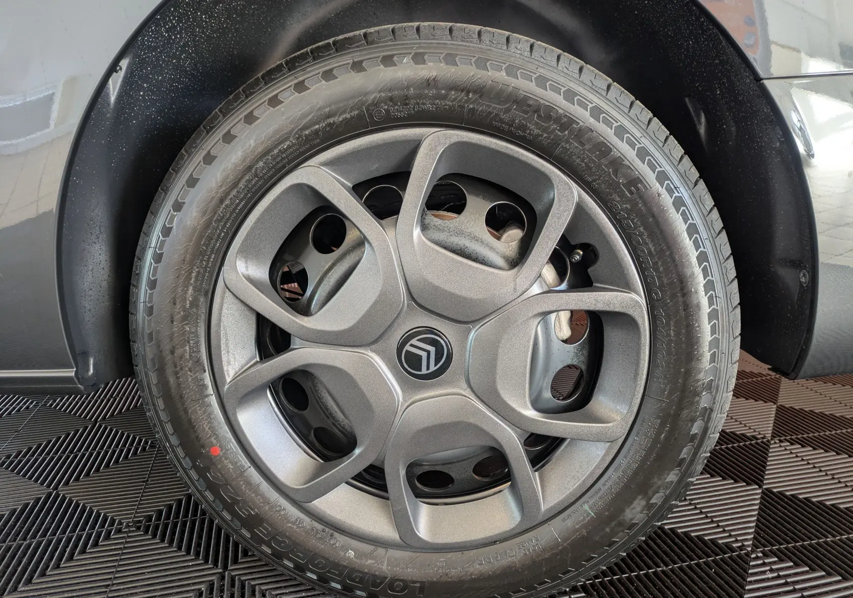 Gros plan sur la roue avant droite gris titane d'un Citroën Jumpy Cabine Approfondie avec jante tôle noire et enjoliveur gris.