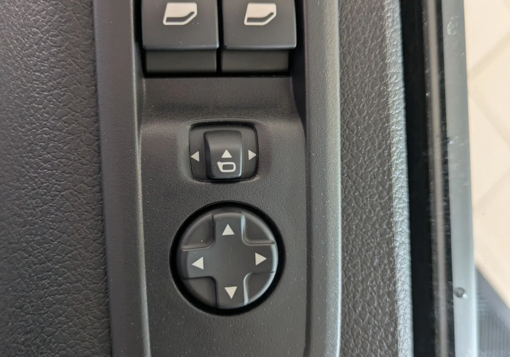 Gros plan sur les commandes de réglage des rétroviseurs et vitres électriques côté conducteur du Citroën Jumpy gris titane.
