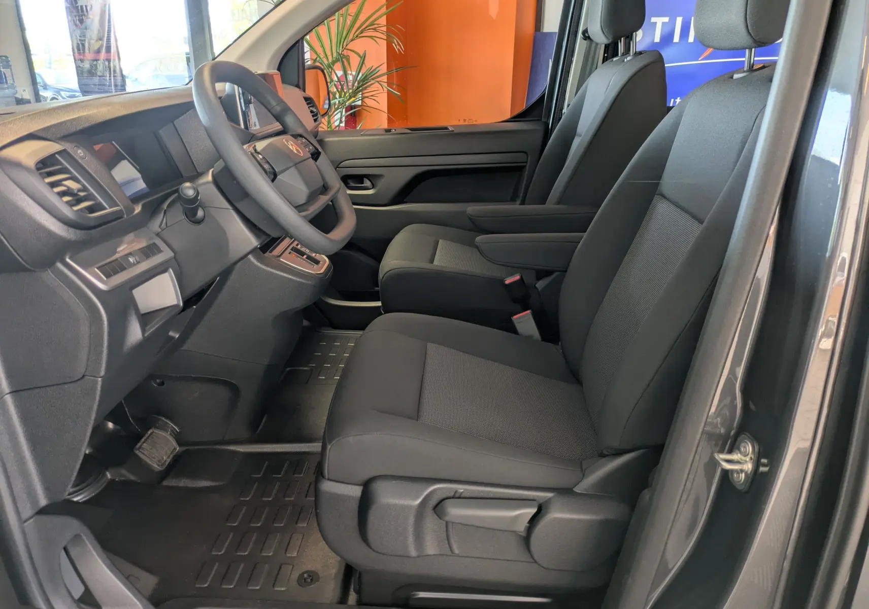 Vue intérieure côté conducteur du Citroën Jumpy Cabine Approfondie gris titane, sièges tissu noir avec accoudoir.