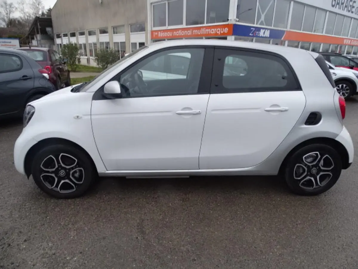 Vue latérale gauche d'une Smart Forfour électrique blanche avec jantes alliage bicolores et toit gris clair.