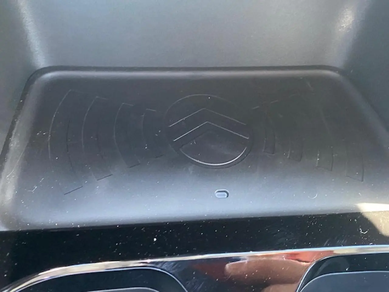 Gros plan sur le chargeur sans fil noir avec logo Citroën intégré, intérieur de la Citroën C3 Aircross 2026.