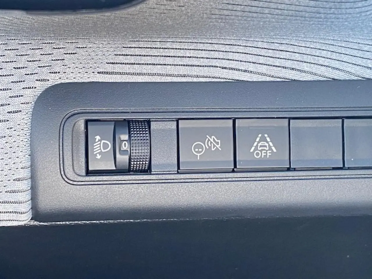Gros plan sur les boutons de réglage d’éclairage et d’aides à la conduite dans l’habitacle gris clair du Citroën C3 Aircross.