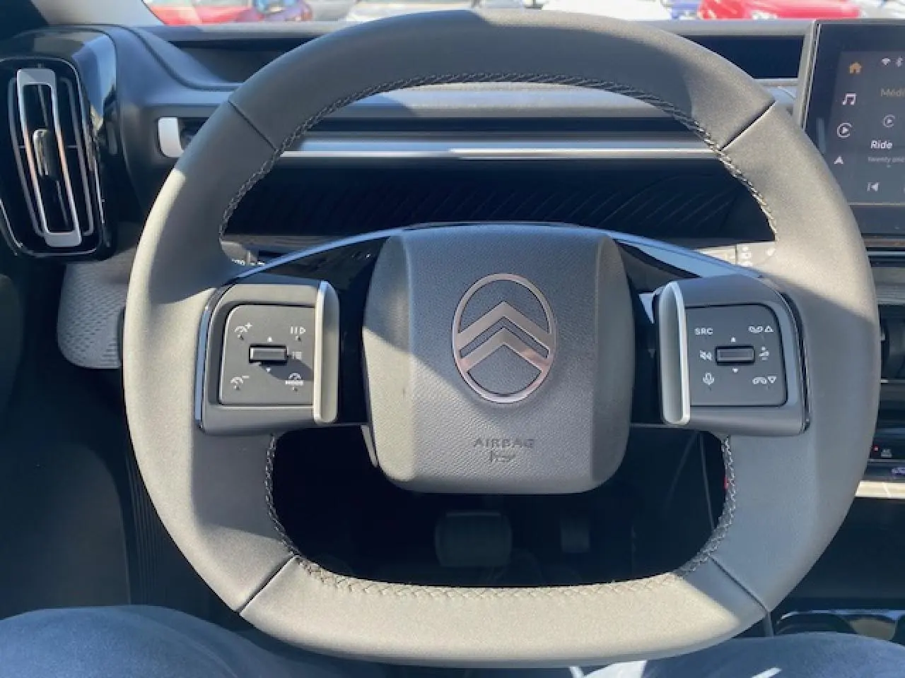 Gros plan sur le volant multifonctions gris du Citroën C3 Aircross 2026 avec logo chevrons et commandes intégrées.