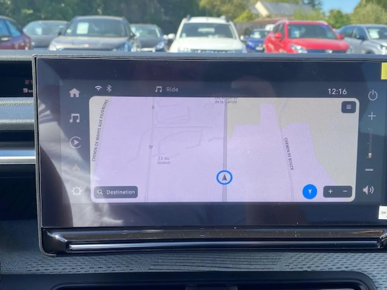 Vue intérieure centrée sur l'écran tactile de navigation du Citroën C3 Aircross 2026, avec tableau de bord gris et environnement extérieur flou.