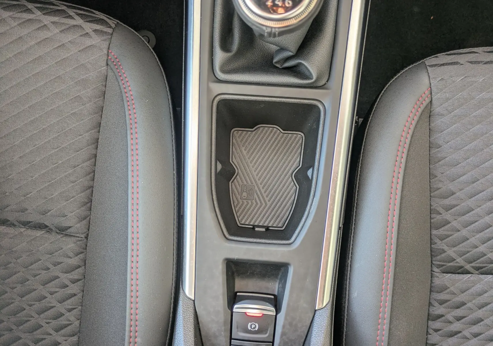 Vue plongeante sur la console centrale de la Renault Clio VI TCe 115ch, boîte manuelle, sièges noirs avec surpiqûres rouges.