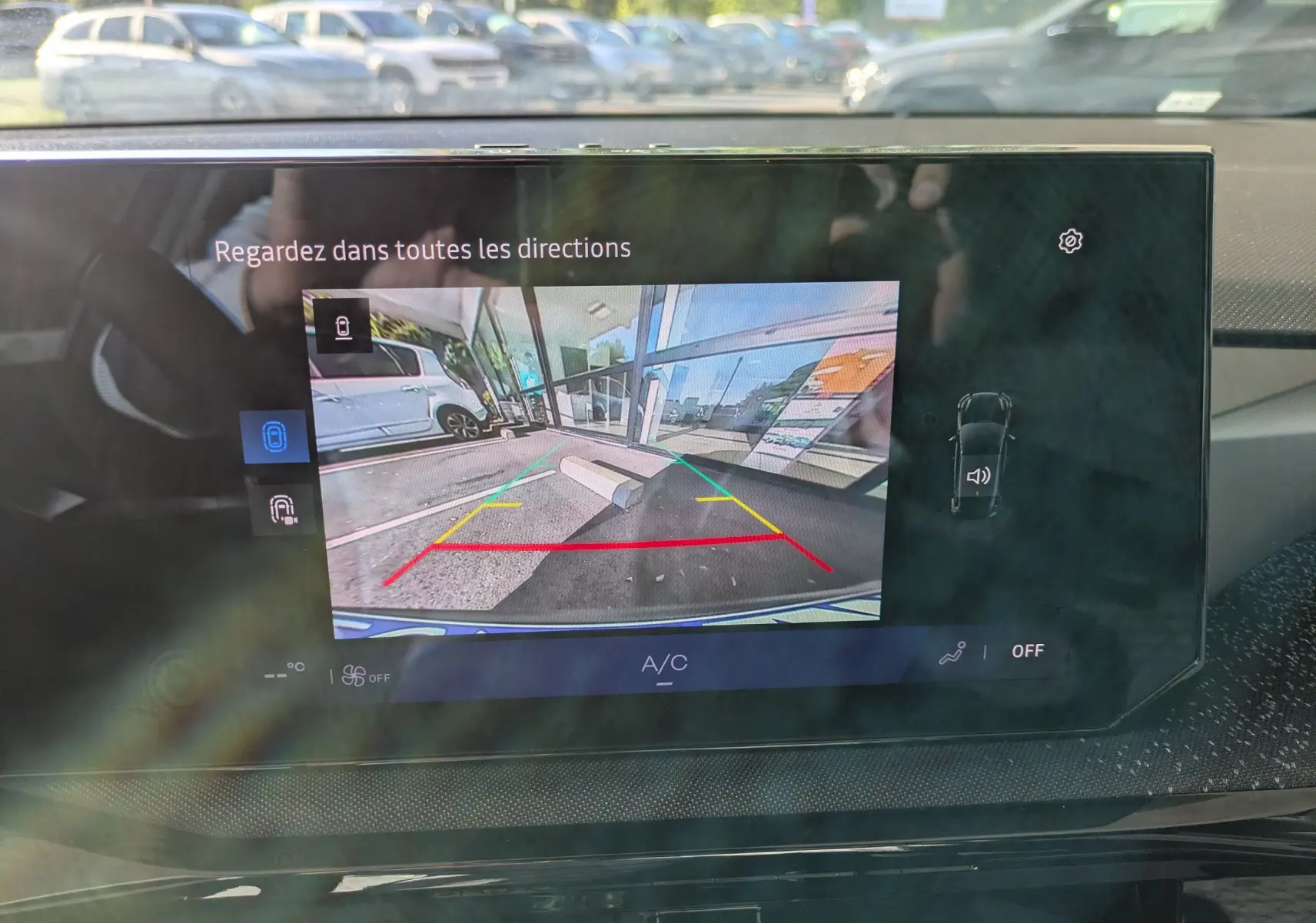 Écran central affichant la caméra de recul d'une Renault Clio VI TCe 115ch Techno, vue arrière avec lignes de guidage colorées.