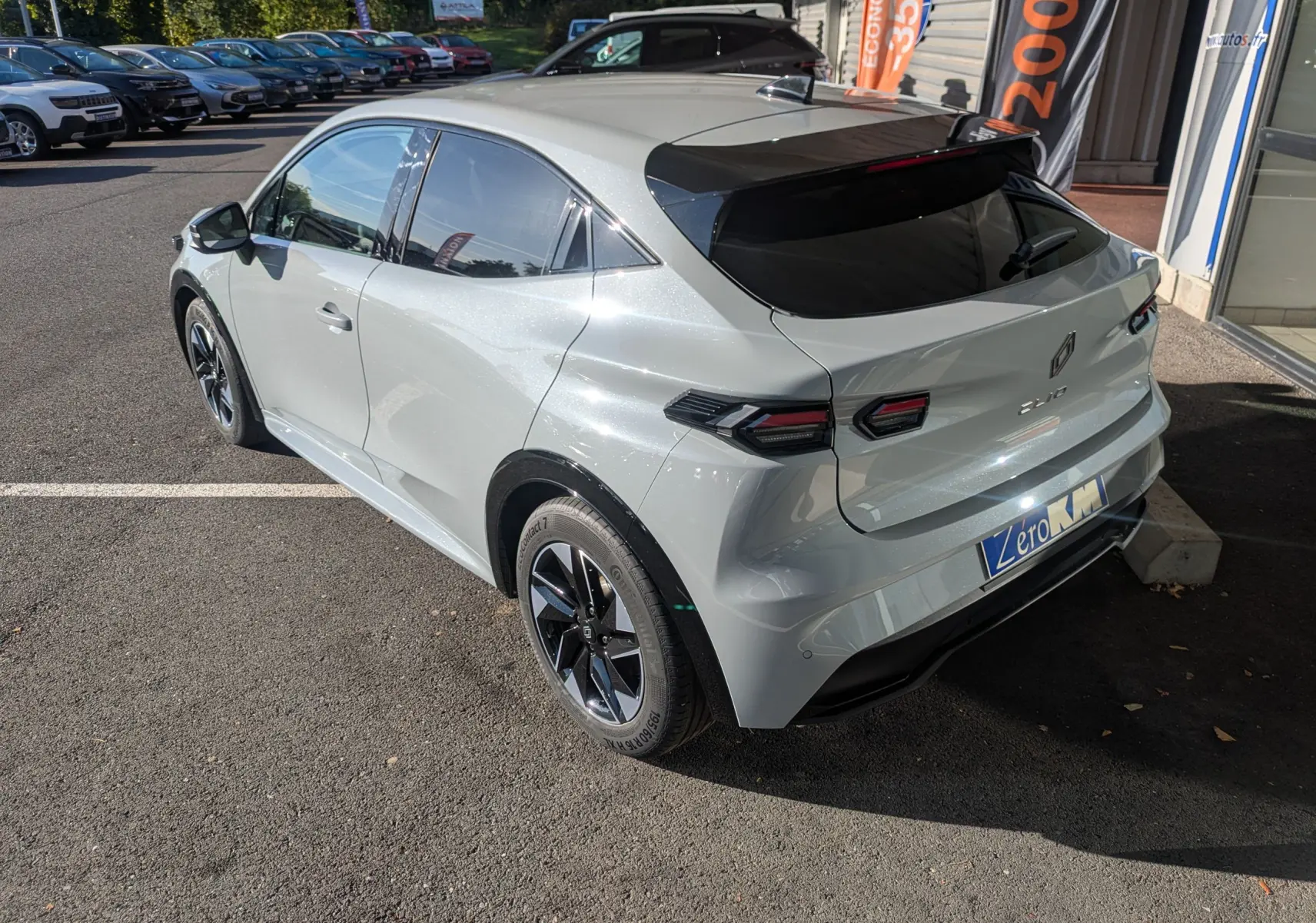 Vue 3/4 arrière droite d'une Renault Clio gris Rafale métallisé avec toit noir et jantes noires.