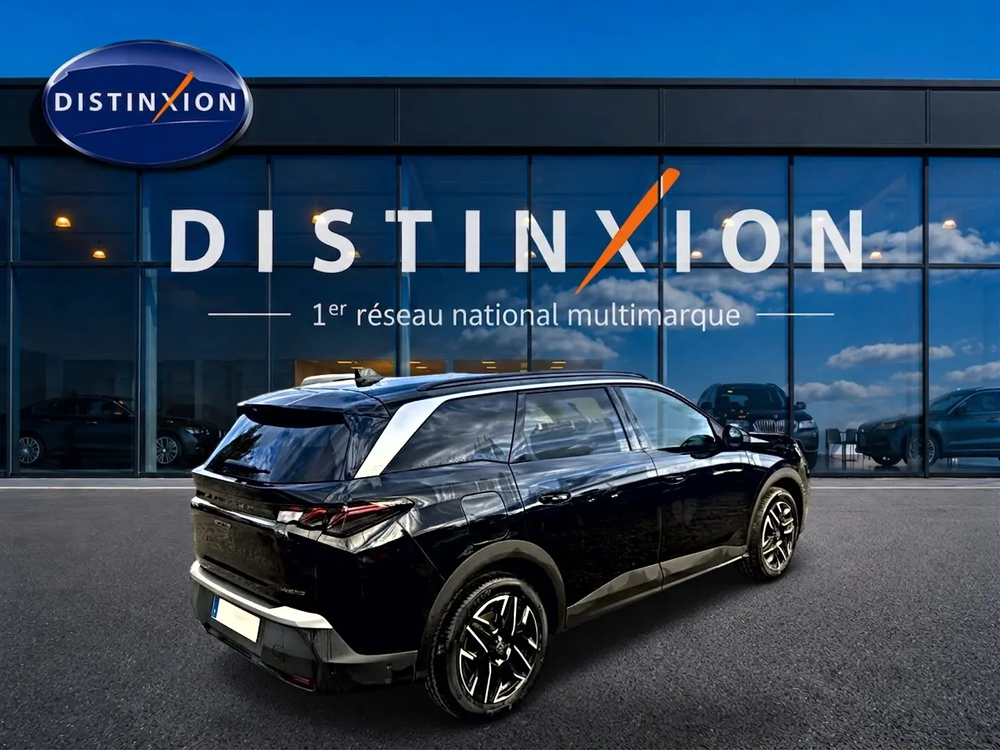 Peugeot 5008 Hybrid 145 GT noir en 3/4 arrière droit, avec jantes alu et toit noir brillant devant showroom Distinxion.