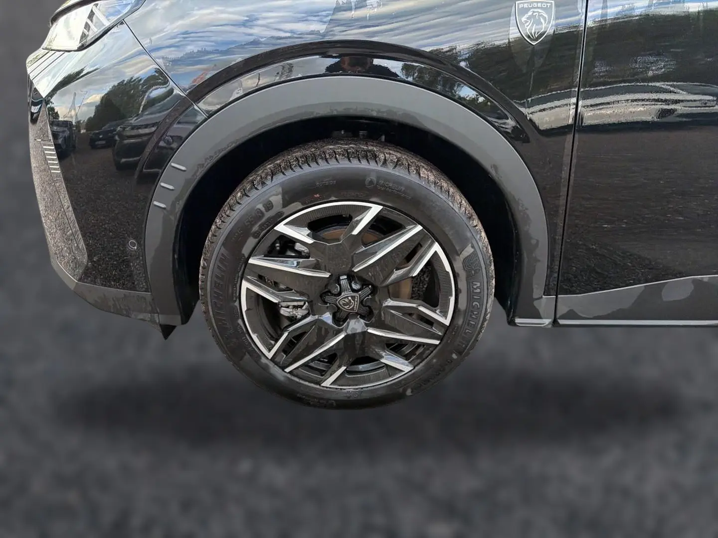 Gros plan sur la roue avant gauche et la carrosserie noire brillante d'un Peugeot 5008 Hybrid 145 GT e-dcs6 2025.