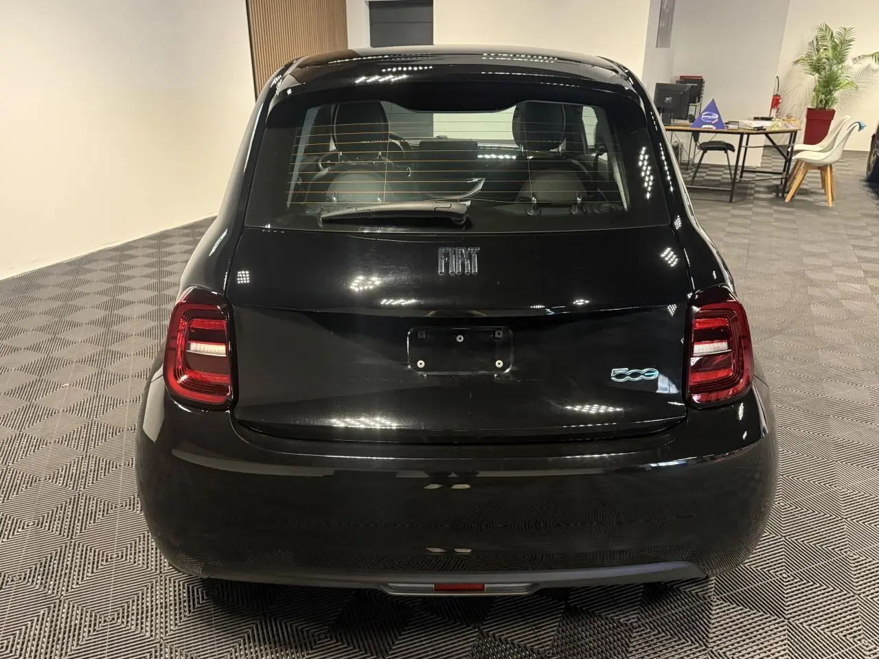 Vue arrière d'une FIAT 500 électrique noire 2024, avec logo 500 lumineux et feux arrière LED rouges.