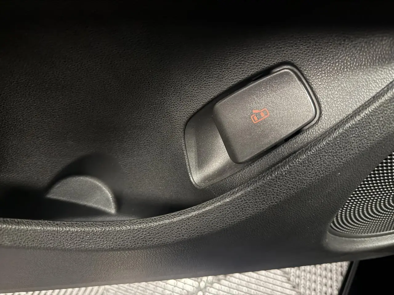 Gros plan sur le bouton de verrouillage des portes côté intérieur d’une FIAT 500 électrique noire 2024.