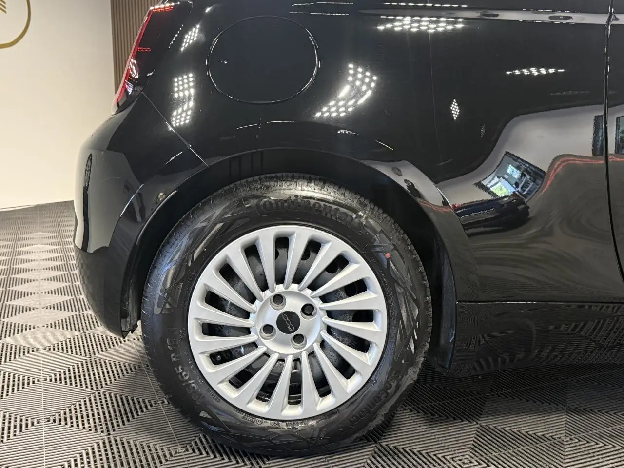 Gros plan sur la roue arrière gauche de la Fiat 500 électrique noire 2024 avec jante acier 15 pouces et logo central.