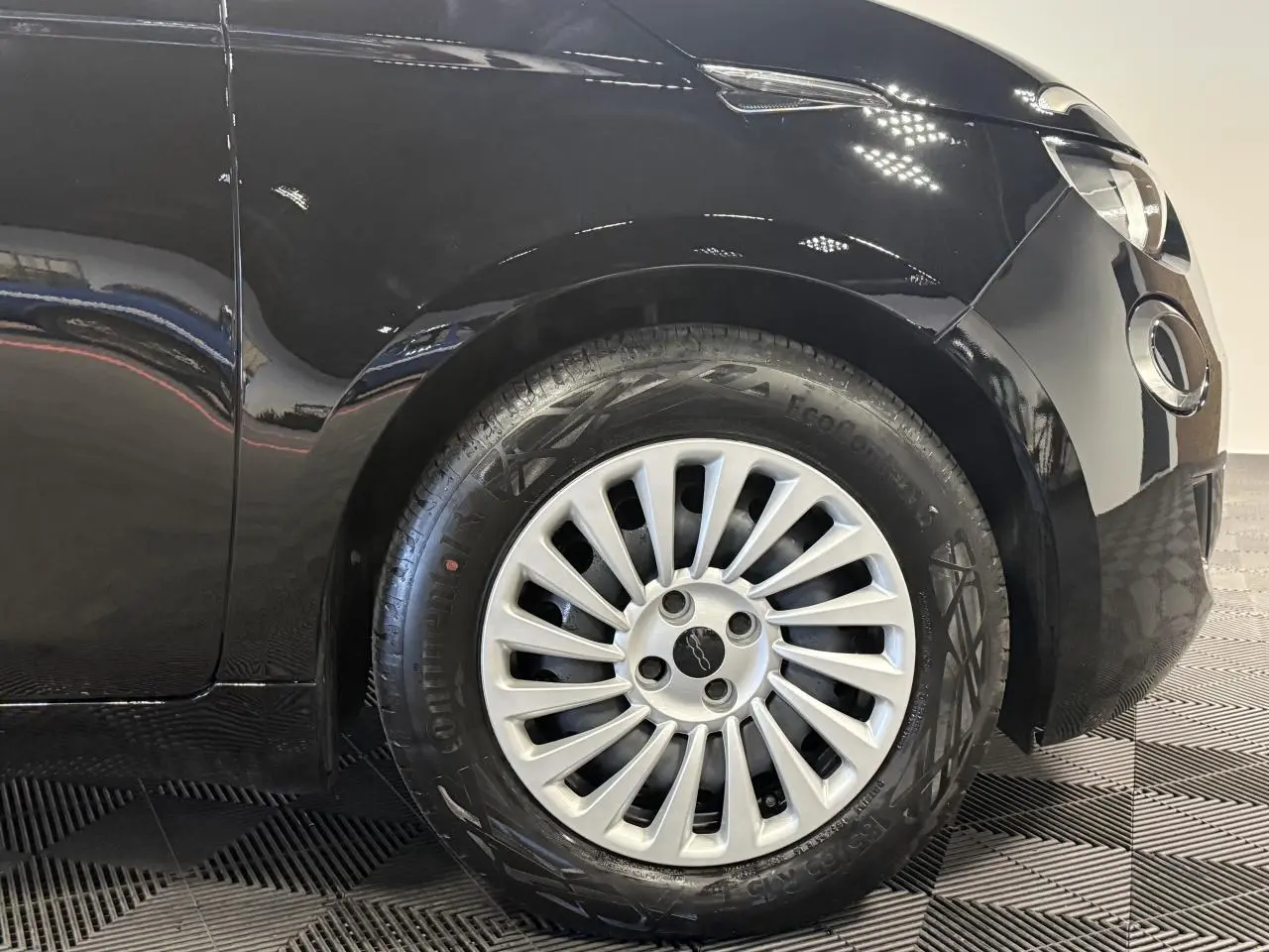 Gros plan sur la roue avant droite d'une FIAT 500 noire 2024 avec jante acier 15 pouces et logo central.