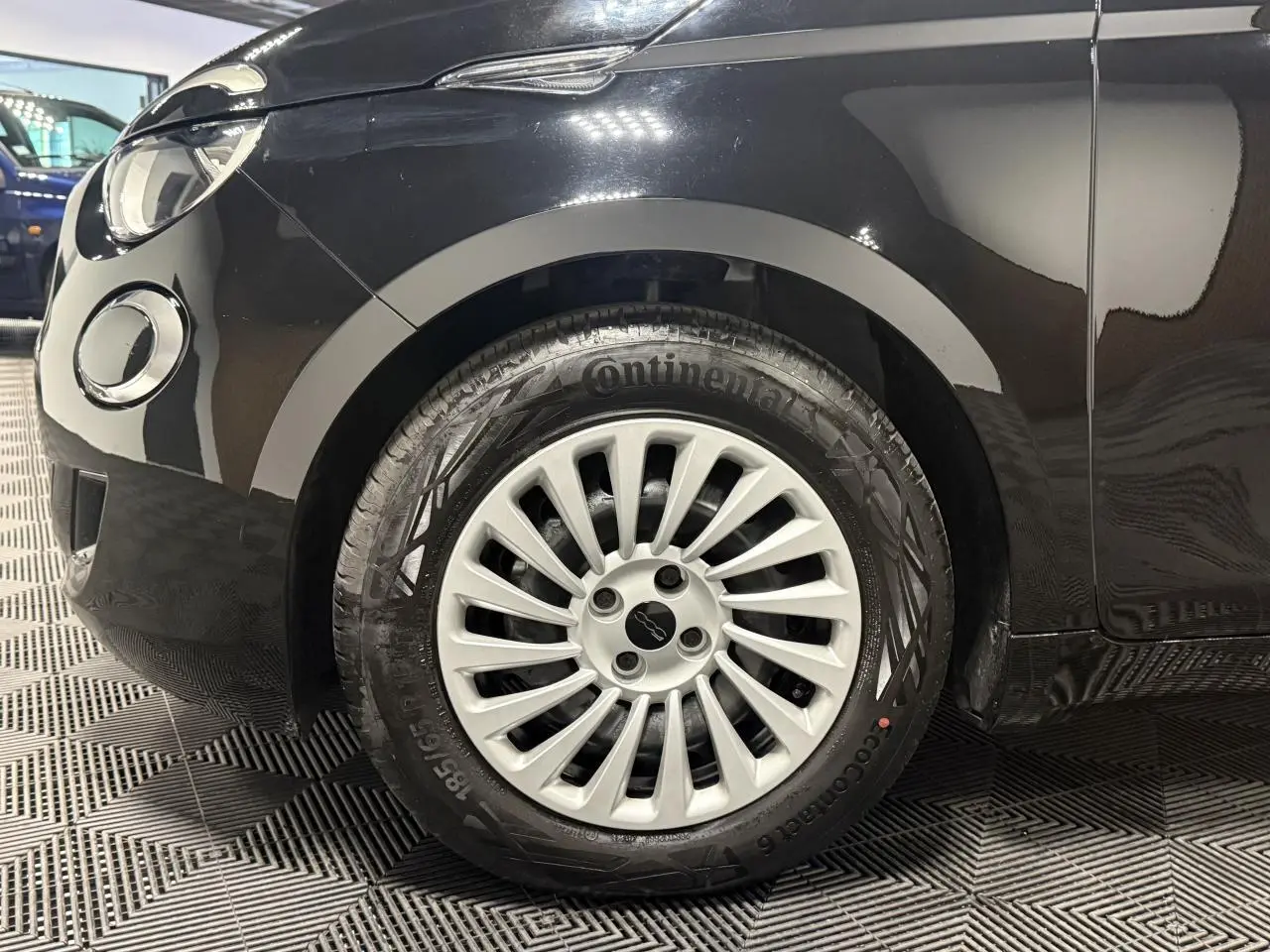 Gros plan sur la roue avant gauche noire d’une Fiat 500 électrique 2024 avec jante acier 15 pouces.