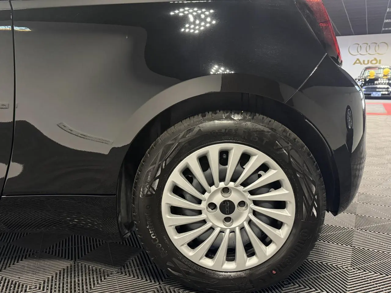 Gros plan sur la roue arrière droite d’une FIAT 500 électrique noire avec jante acier 15 pouces et logo central.
