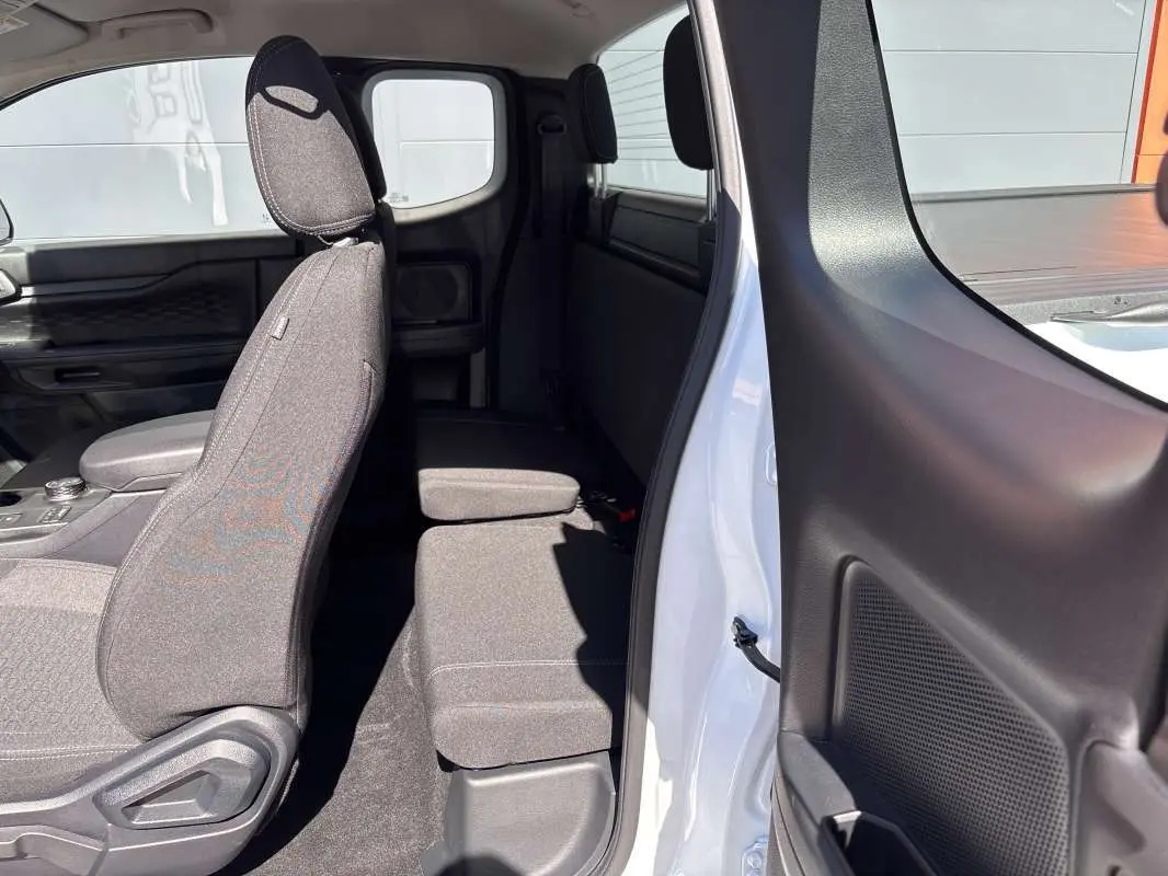 Vue intérieure côté droit du Ford Ranger blanc glacier 2026, montrant les sièges avant et arrière en tissu gris.