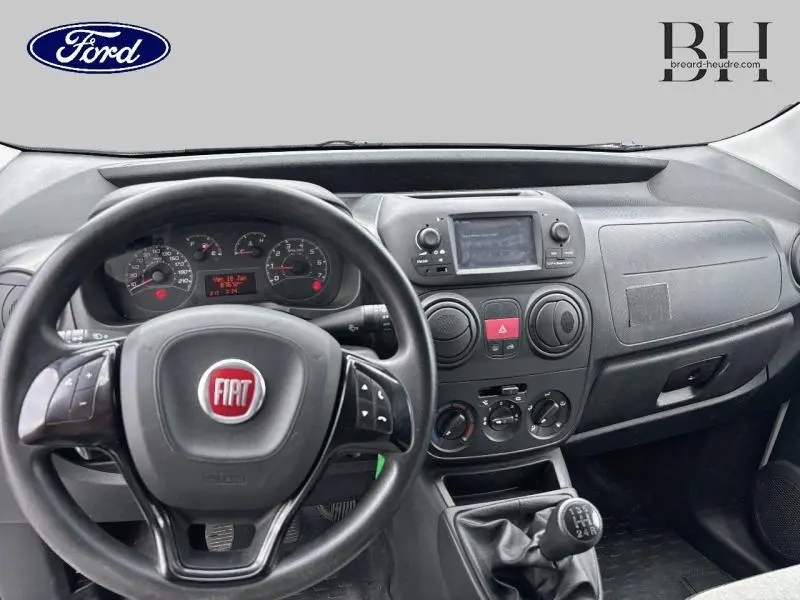 Vue intérieure du tableau de bord et volant noir du Fiat Fiorino blanc, avec écran tactile et commande manuelle de vitesses.