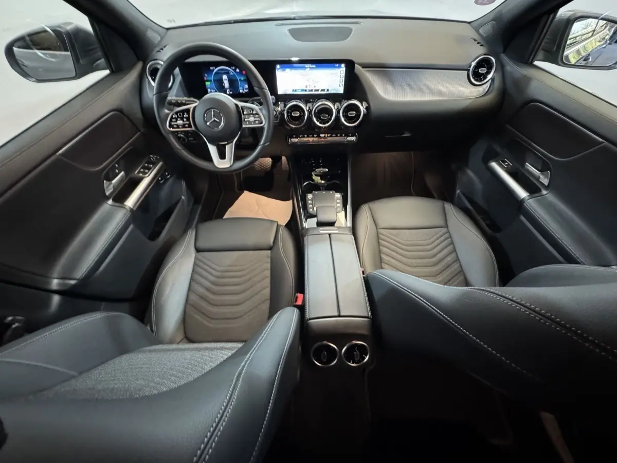 Vue intérieure avant du Mercedes GLA 250 e Business Line 2023, sièges cuir noirs et tableau de bord digital avec écran tactile central.