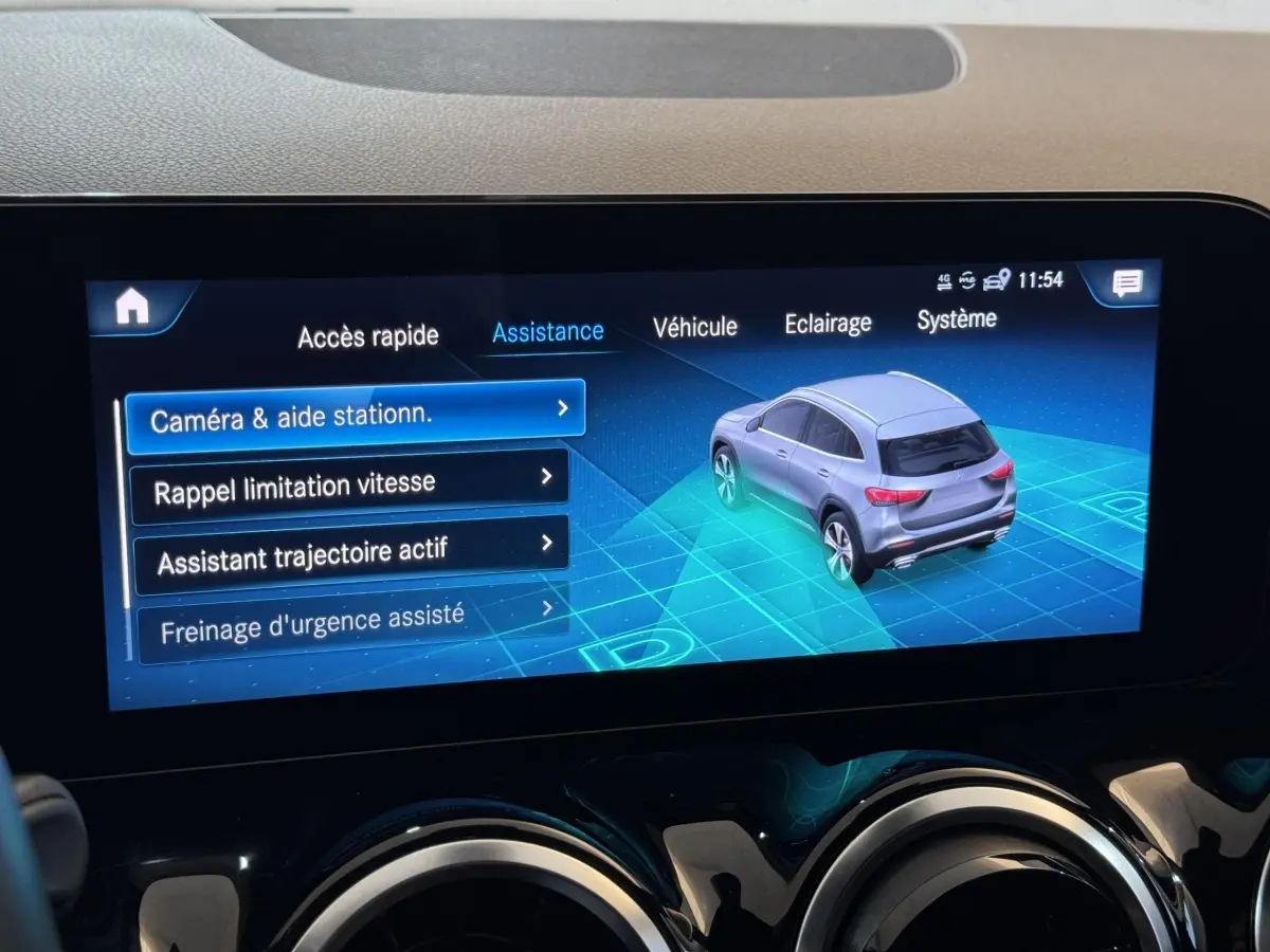 Écran tactile central montrant l'assistance au stationnement avec vue 3/4 arrière d'un Mercedes GLA gris foncé.