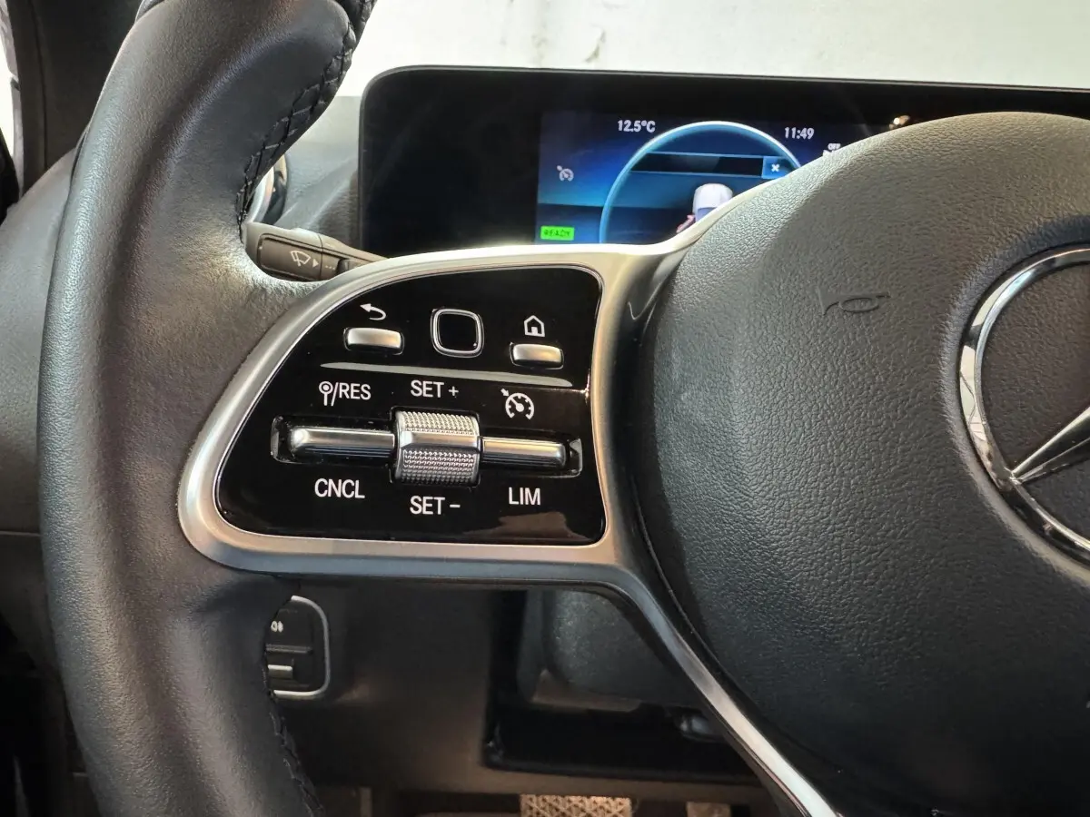 Gros plan sur les commandes gauche du volant cuir noir du Mercedes GLA 250 e Business Line 2023 avec affichage numérique.