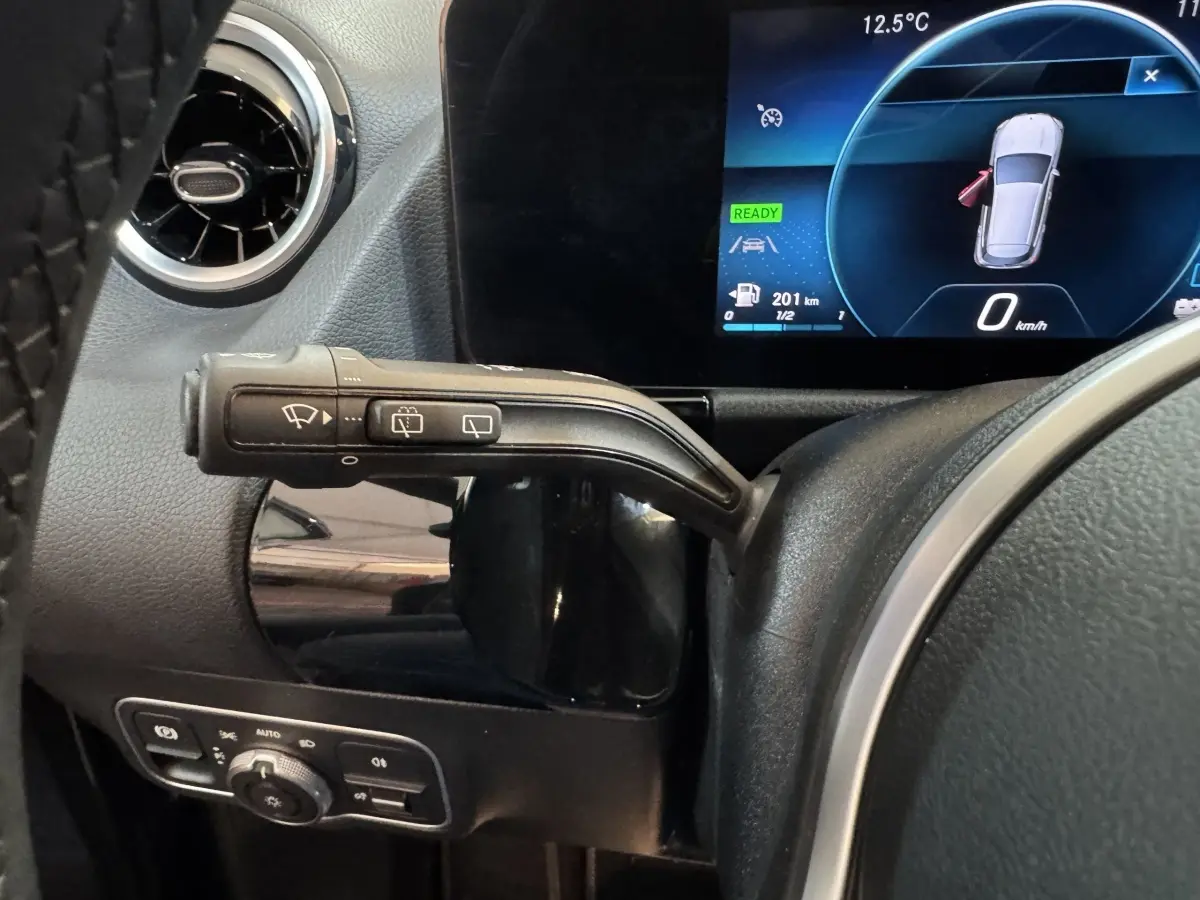 Gros plan sur la commande d’essuie-glace à gauche du volant d’un Mercedes GLA 250 e gris foncé avec tableau de bord numérique.