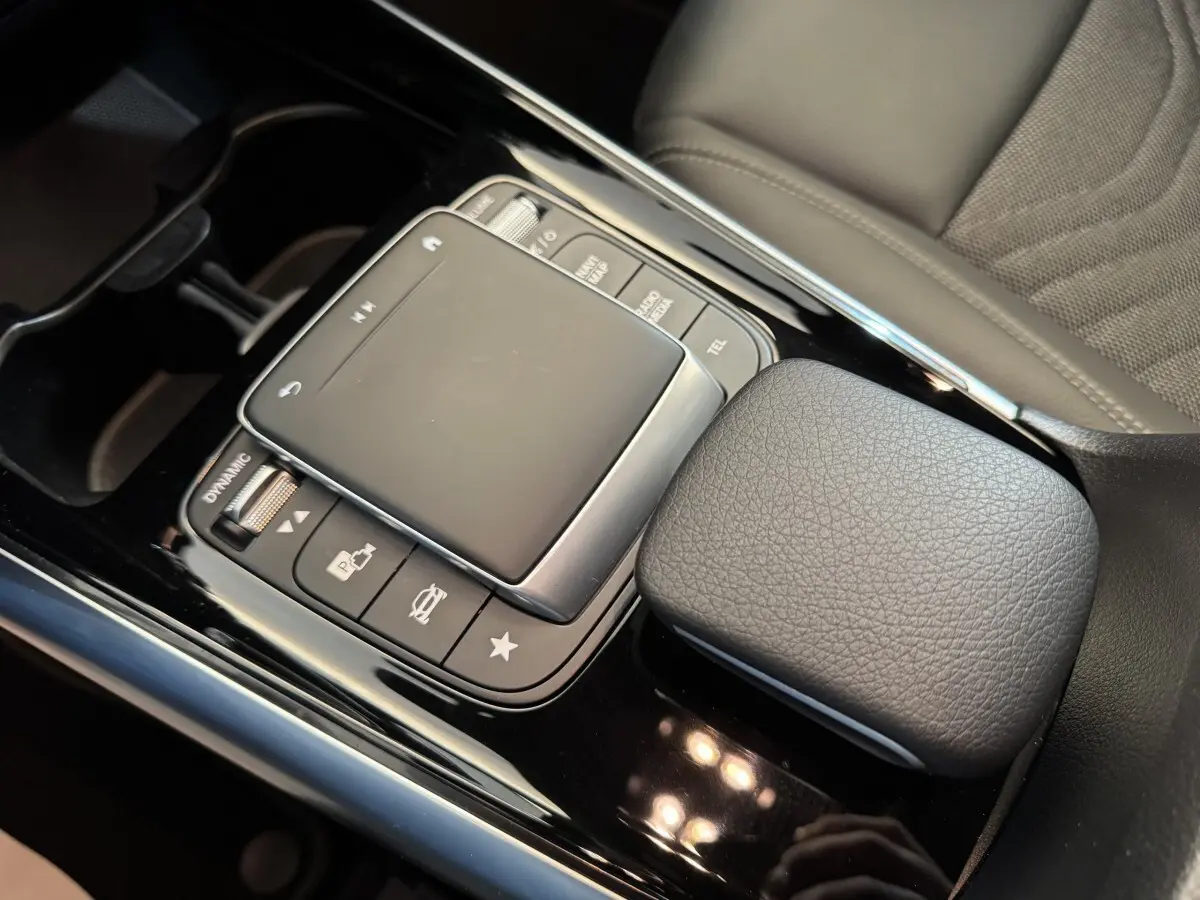 Gros plan sur la console centrale noire avec pavé tactile et accoudoir en cuir gris du Mercedes GLA 250 e Business Line 2023.