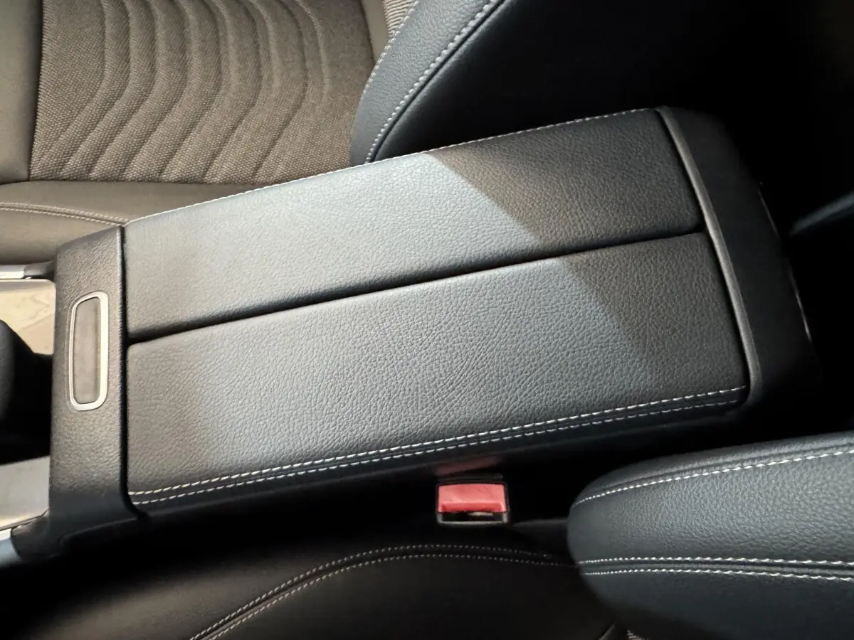 Vue rapprochée de l'accoudoir central en cuir noir avec surpiqûres blanches dans l'habitacle du Mercedes GLA 250 e gris foncé.