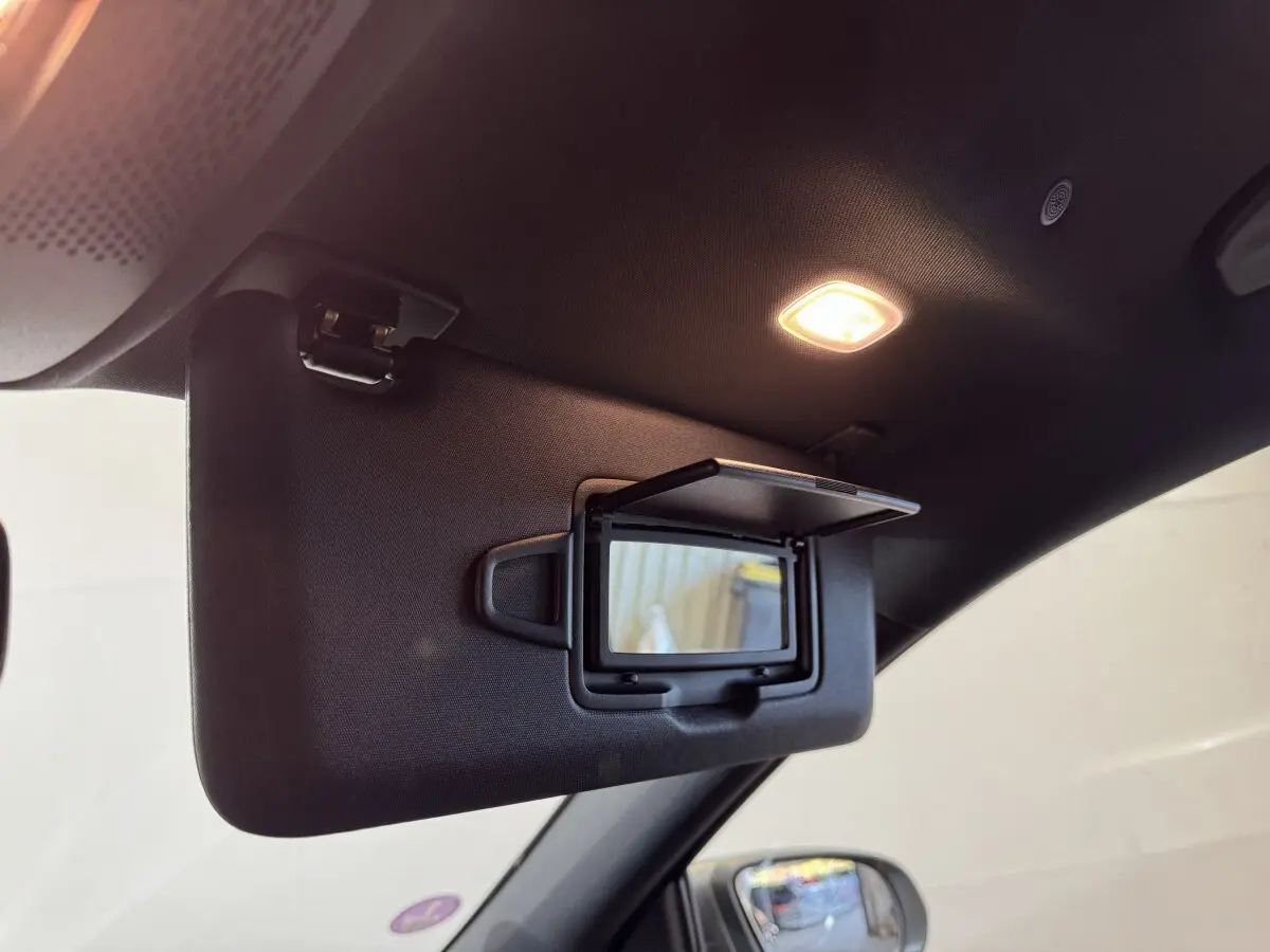Vue intérieure rapprochée du pare-soleil côté conducteur avec miroir éclairé dans un Mercedes GLA 250 e gris foncé 2023.