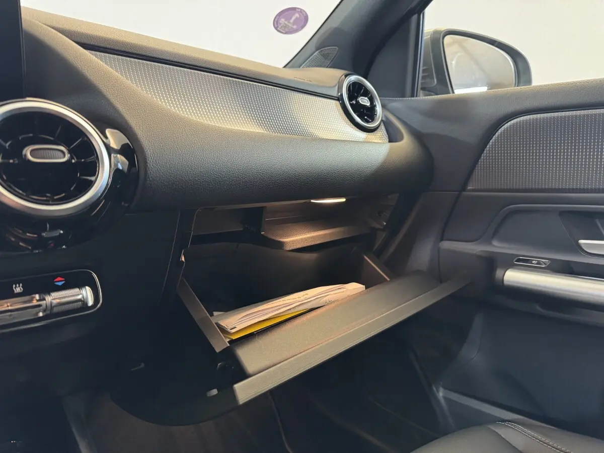 Intérieur du Mercedes GLA 250 e Business Line 2023, vue côté passager avec boîte à gants ouverte et détails noirs et argentés.