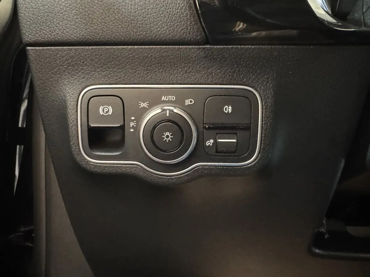 Gros plan sur le panneau de commande des phares et du frein à main électrique, intérieur noir du Mercedes GLA 250 e.