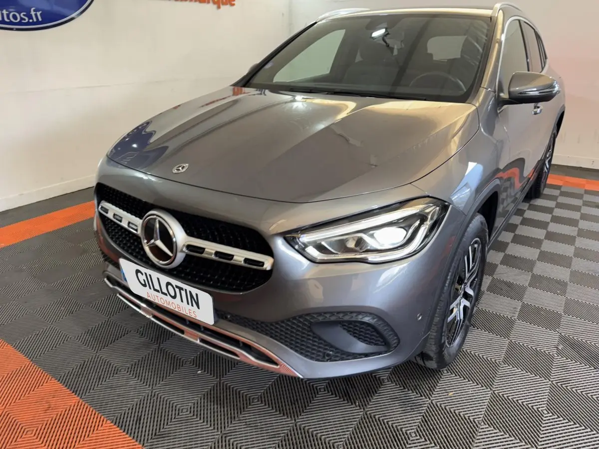 Mercedes GLA 250 e Business Line gris foncé vue 3/4 avant avec phares LED allumés et calandre chromée.