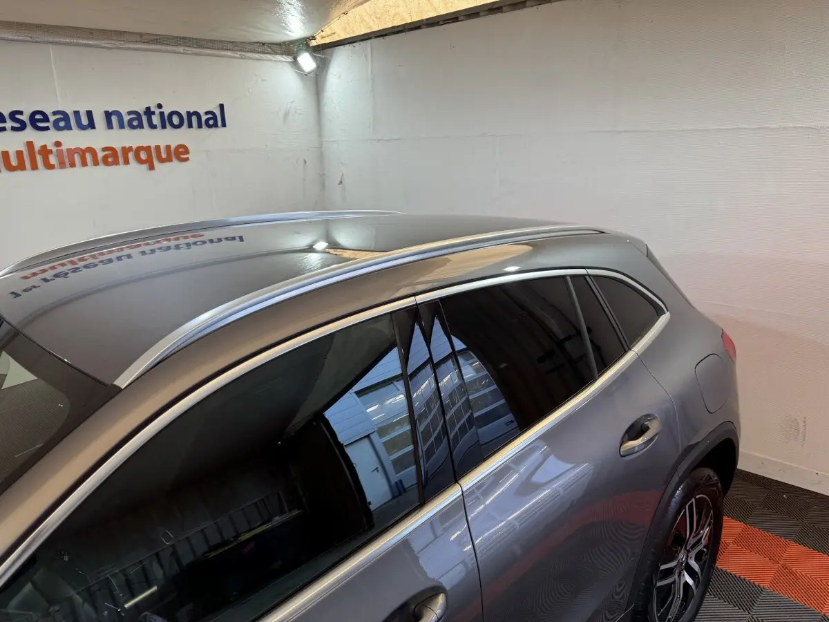 Vue 3/4 arrière droite d’un Mercedes GLA 250 e Business Line gris foncé avec vitres teintées et barres de toit chromées.